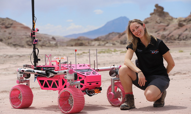 Image of Rebecca Leith crouching next to the pink rover