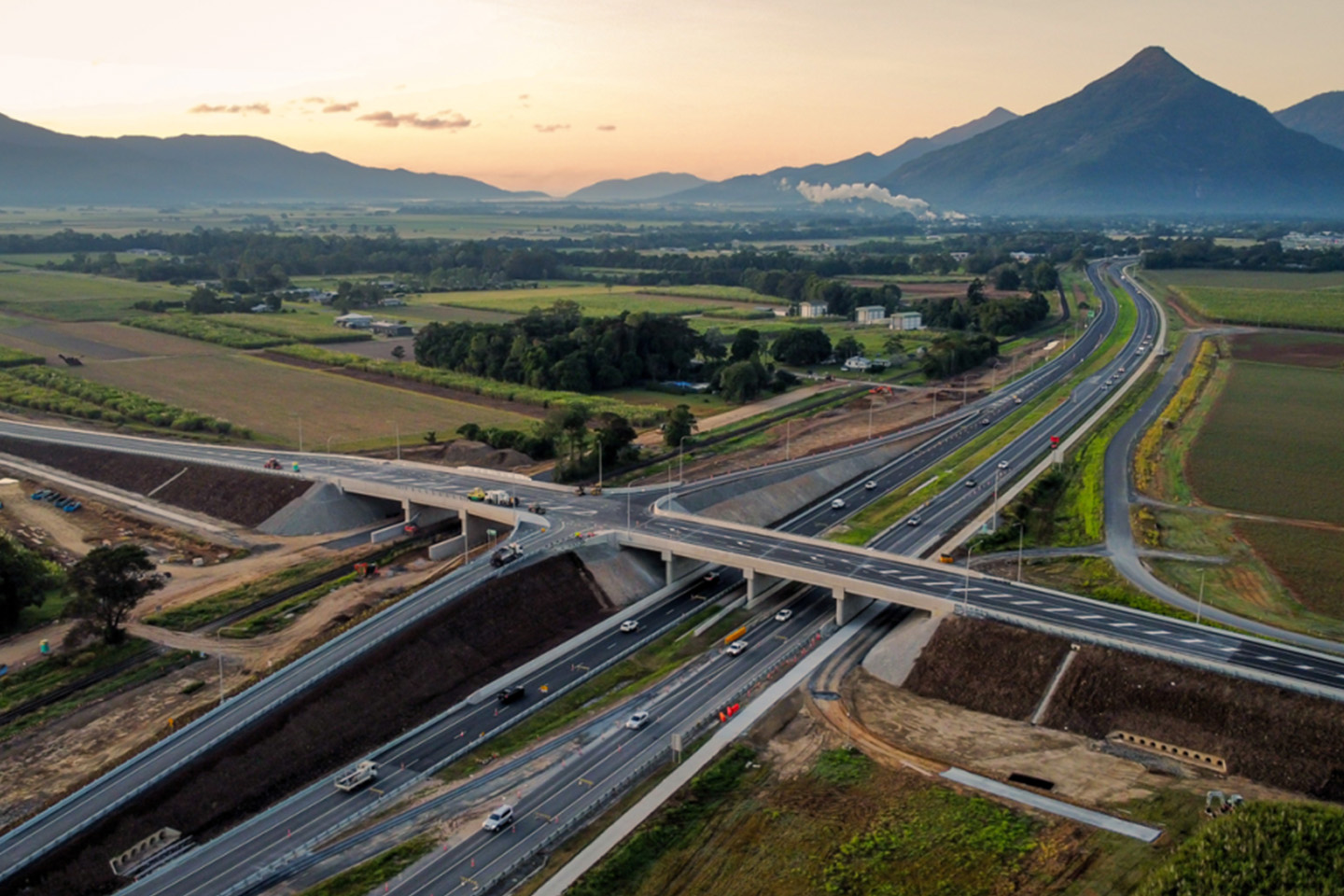 Aerial shot of a road construction site with mountains in the background as the sun sets